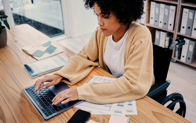 Woman using a laptop with financial documents on her desk
