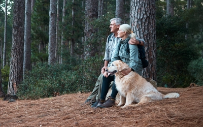 Retired couple hiking with their dog in a forest